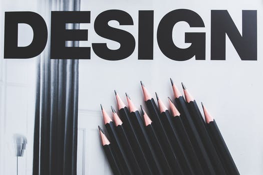 black and white image displaying black pencils and the word "Design" in bold letters